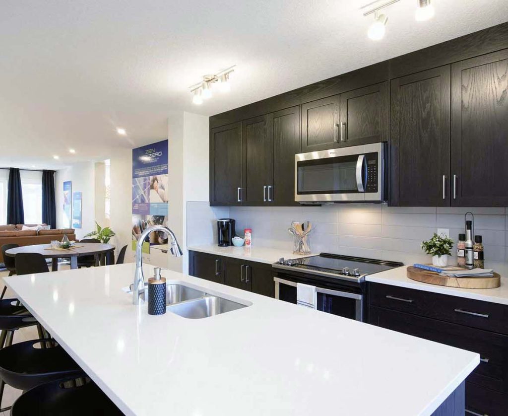 Spacious ZEN Ambrosia kitchen by Avalon Homes featuring dark wood cabinetry, quartz island, and open-concept dining area.