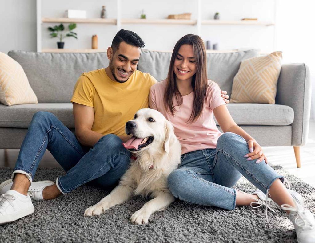 Happy young couple sitting on the floor with a dog
