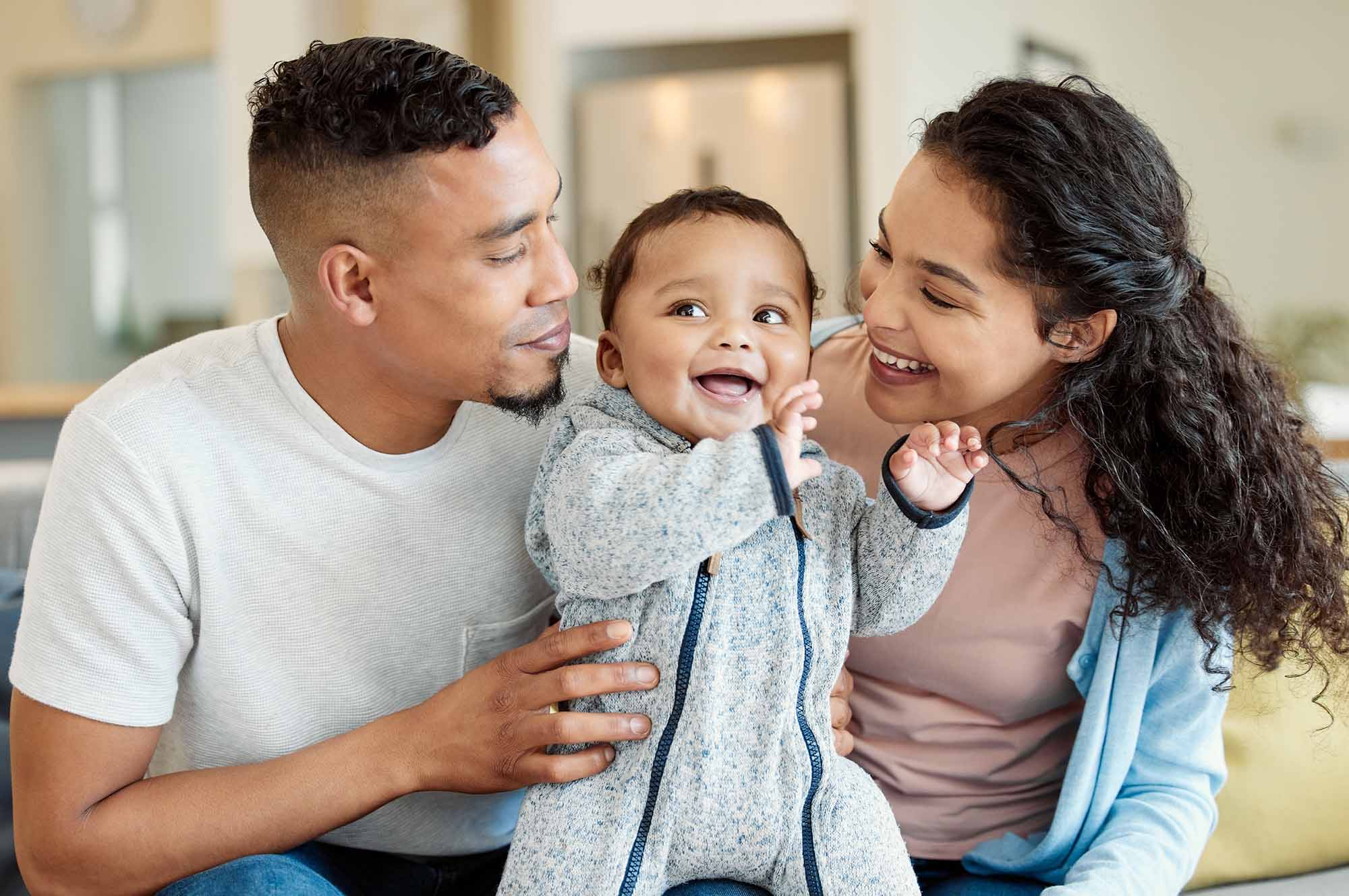 A happy young couple with a cute baby between them in a net zero home