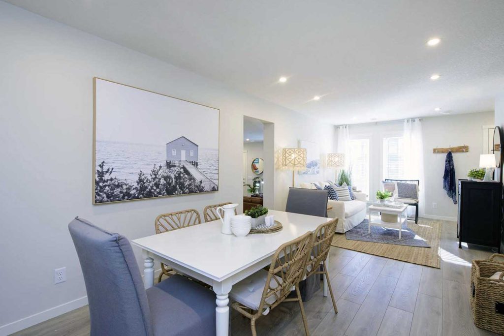Open-concept dining and living area in a modern townhouse with natural light, neutral tones, and coastal decor.