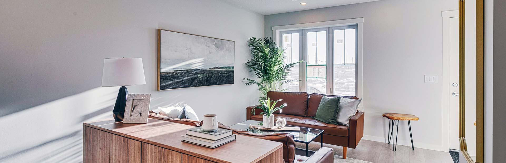 Modern ZEN Livingston living room with brown leather sofas, natural light, and minimalist decor in a Net Zero townhome.