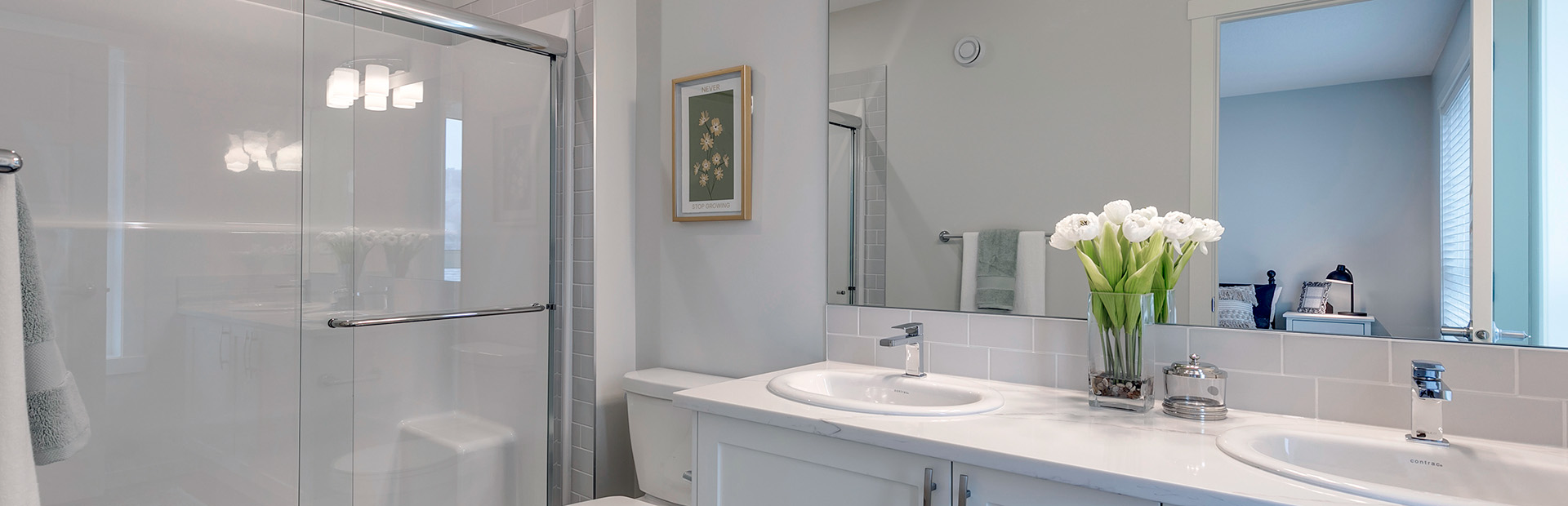 Modern Greystone bathroom by Avalon Homes featuring dual sinks, quartz countertop, glass shower, and contemporary finishes.