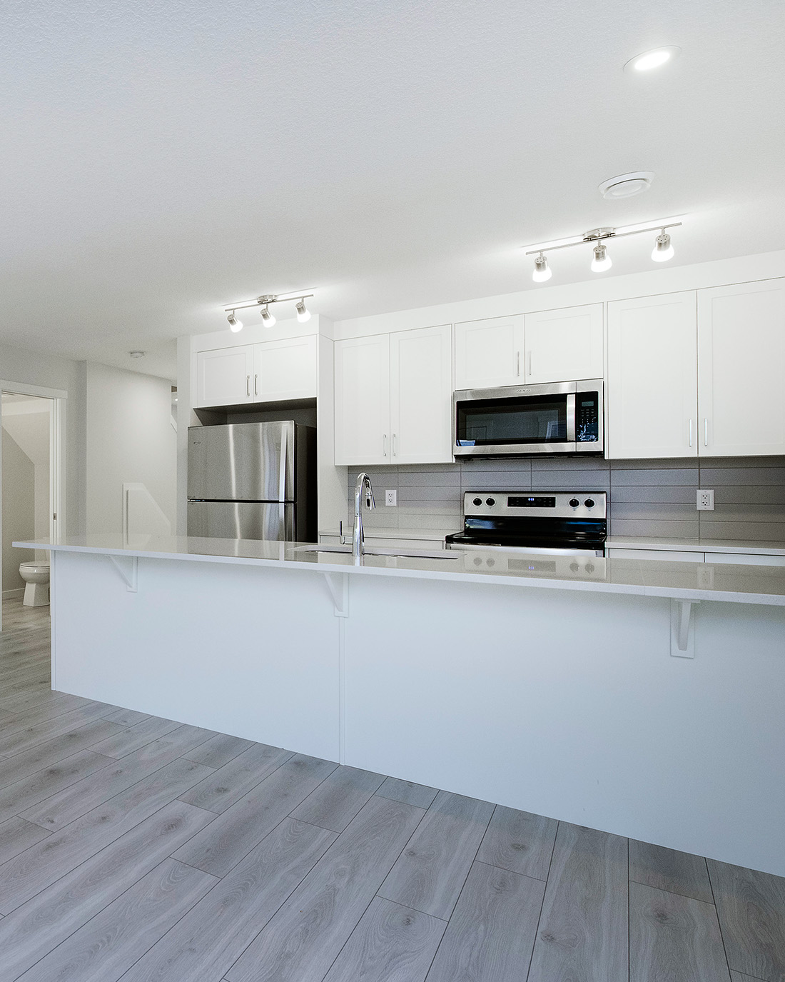 Bright white kitchen in Avalon Homes’ ZEN townhouse featuring stainless steel appliances, quartz countertops, and modern finishes.