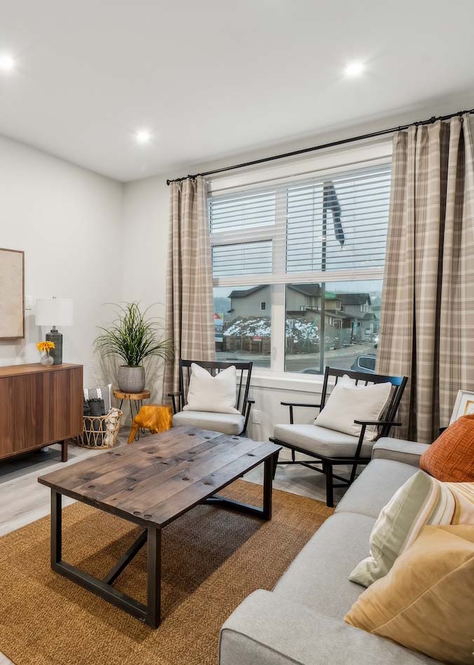 ZEN Greystone showhome living room with large window, modern furniture, neutral tones, and wood-accented decor by Avalon Homes.