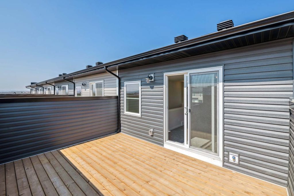 Private rooftop patio with wood decking and sliding glass door access on a modern townhouse.