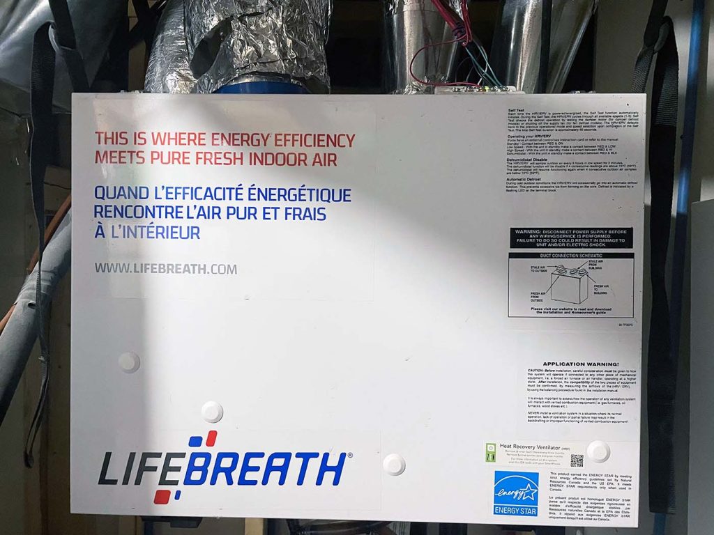 Lifebreath heat recovery ventilator (HRV) unit installed in a utility area, with visible ductwork and a label highlighting energy efficiency and improved indoor air quality.